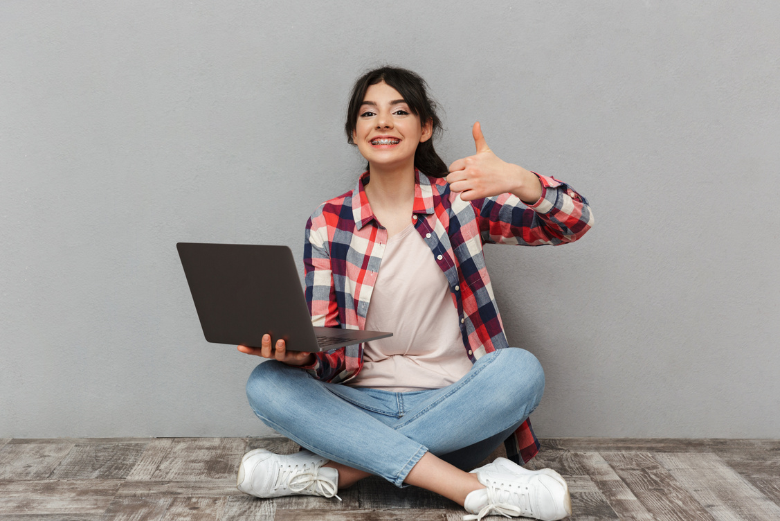 Happy Young Lady Student Holding Laptop Computer Make Thumbs up.